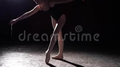 灵活的年轻<strong>芭蕾舞</strong>演员站在她的尖角<strong>芭蕾舞</strong>鞋在聚光灯下的黑色背景在工作室。 慢<strong>动作</strong>。