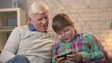 祖父和孙子坐在沙发上用智能手机说话，一个胖孩子在玩智能手机。 青年