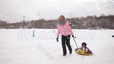 快乐的妈妈和女儿在冬天的雪中雪橇，玩雪球。 母亲和孩子笑着快乐<strong>地滑</strong>行