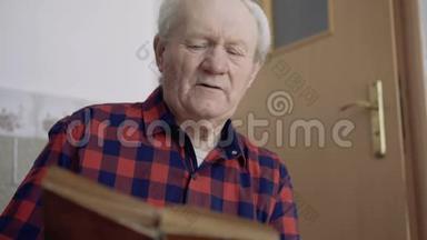 有皱纹的老人在房间里读着思考的书。 4K