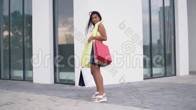 漂亮的女孩模特购物后，手里拿着彩色的袋子。 慢动作。 高清高清