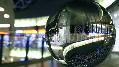 不知名的顾客走在现代化的商场里.. 在玻璃球体中扭曲的视野