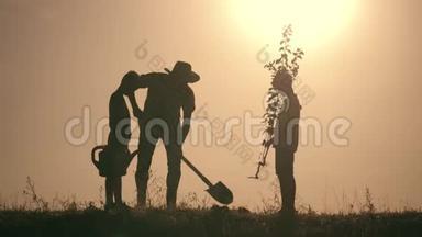 一个<strong>幸福</strong>的家庭。 父亲和两个儿子在日落时在公园里种树并浇水。 <strong>幸福</strong>家庭的概念