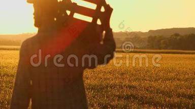 农夫拿着铲子和盒子在田里散步。 他们携带种植树木的设备。 在日落的时候。 侧视图