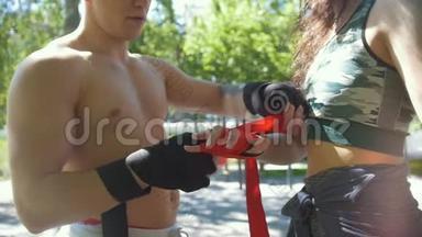 男拳击手包手年轻女子帮他，在公园锻炼-慢动作
