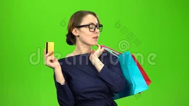 拿着一袋纸的女人手里拿着一张卡片去购物。 绿色屏幕