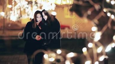 两个女孩在夜间散步时被拍照。 在平安夜自私的两个女孩。
