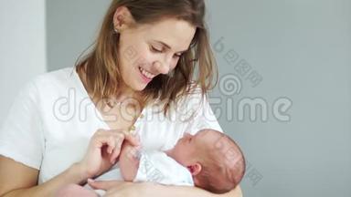 一个女人怀里抱着一个新生婴儿。 孩子看着他的母亲，用一张没有牙齿的嘴微笑。 母亲