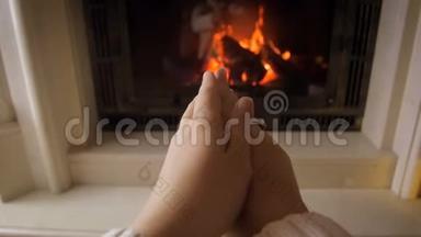 在寒冷的冬日，一位年轻女子因燃烧着的火而暖手的特写镜头
