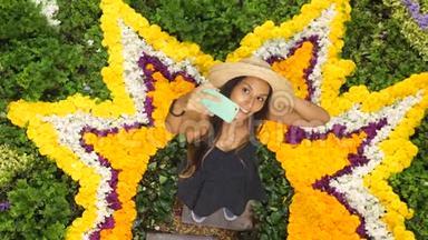 年轻迷人的少女利用手机在美丽的花团锦簇背景。 4K.