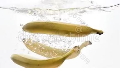 特写三根香蕉在白色背景下落水的慢镜头
