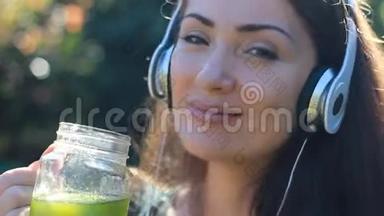 女人喝着绿色冰沙，听着音乐带着<strong>耳机特写</strong>镜头