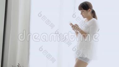 美丽的肖像年轻的亚洲女人微笑着站着看着智能手机阅读社交网络