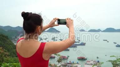这位女士从岛的顶端拍摄一个海湾的照片。 这位女士要花很多钱去观看