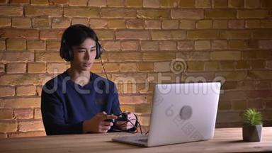 在室内使用笔记本电脑玩电子游戏的<strong>耳机</strong>中，年轻韩国男学生的<strong>特写</strong>照片