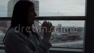 年轻女子在咖啡馆里喝着刚榨的果汁，看着窗外的特大城市背景。