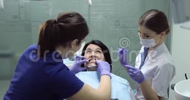 牙科<strong>护士</strong>坐在<strong>病人</strong>旁边，牙科医生用镜子开始治疗<strong>病人</strong>