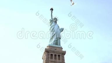 著名的自由女神像国家纪念碑在纽约自由岛在一个晴朗的夏天，一只大鸟飞过。