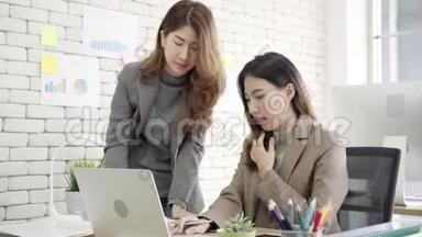 两位年轻的亚洲女商人在<strong>小企业</strong>的办公室里一起工作，坐着看报告或文件。