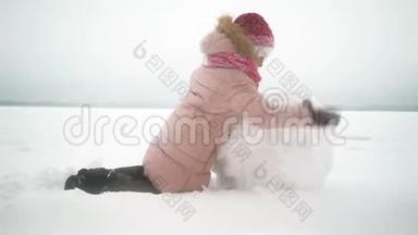 女孩在冬天为雪人滚动大雪球。