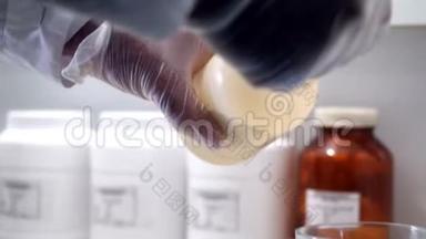 实验室工作人员使用天平。 化学家戴着手套，把<strong>流沙</strong>放在玻璃杯上