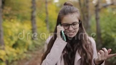 少女在公园里散步，在手机，智能手机上聊天。 秋天的<strong>天气</strong>，黄叶和<strong>凉</strong>爽