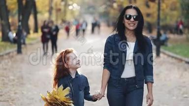 一位美丽的母亲和她可爱的小女儿在<strong>秋</strong>天的公园里散步。 他们在人群中间走<strong>来</strong>走<strong>去</strong>