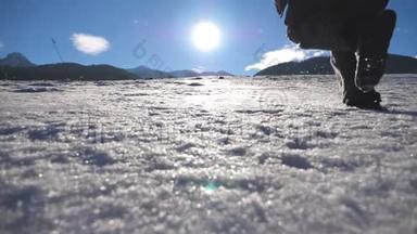 无法辨认的家伙在阳光明媚的冬日在雪地里慢跑。 一个年轻的男人在雪地草地上奔跑。 阳光和蓝天