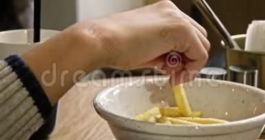 一个十几岁的男孩从桌上的碗里拿薯条的特写视频