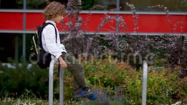一个悲伤的男孩坐在学校附近院子里的栏杆上。 那个<strong>小学生</strong>起来伤心地走了。 <strong>心理</strong>