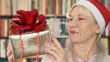 有礼物的高级女人。 戴红帽子、带红丝带礼盒的退休人员庆祝圣诞节