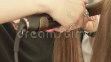 发型师用发钳和梳子为美容院的头发矫直时尚模特。 关闭美发师