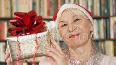 有礼物的高级女人。 戴红帽子、带红丝带礼盒的退休人员庆祝圣诞节