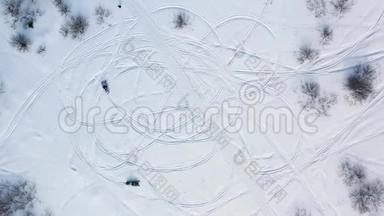 在冬天的森林里，人们在雪地摩托上的空中景色在靠近树木的一片雪草地上赛车。 录像。 冬季赛车