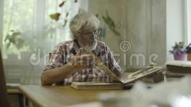 老人坐在家里，看着他的旧专辑和照片