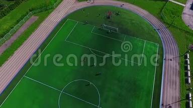 美丽的绿色足球场.. 青少年踢足球。 一只鸟飞行`足球场。