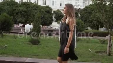 穿着黑色短裙的时髦年轻女子在公园<strong>散步</strong>的慢动作<strong>视频</strong>