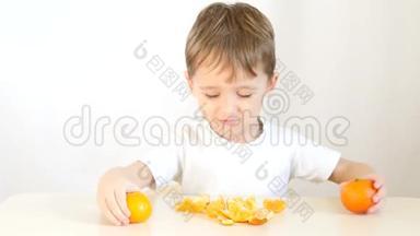小孩玩橘子。 快乐的孩子坐在桌子旁，双手把橘子涂在眼睛上。
