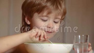 饥饿的小男孩在吃东西。 童年。 孩子在家吃健康的食物。 微笑快乐可爱宝宝吃水果泥