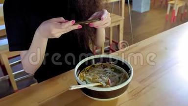 一个可爱的年轻亚洲女孩在亚洲咖啡馆里拍了一张pho汤的照片。 中国、越南或日本咖啡馆或餐馆