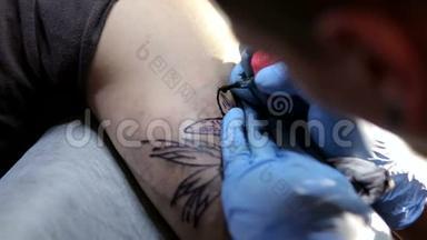 一个戴蓝色手套的男人为一个残忍的男人在手臂上做纹身的特写镜头。