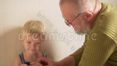快乐的老人从他的<strong>手</strong>和脸到他的小儿子，用<strong>毛巾擦</strong>拭他的<strong>手</strong>。 父亲照顾