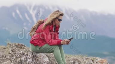 旅行者在山上放松时使用智能手机。 女游客拿着手机