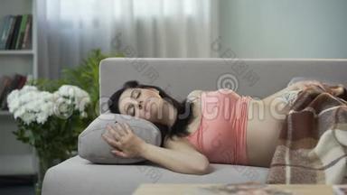 美丽的孕妇甜美地睡在沙发上，<strong>抱着</strong>肚子<strong>抱着婴儿</strong>