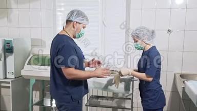 医生团队正在为手术做准备。 护士助理帮助外科医生戴上白手套。 医疗