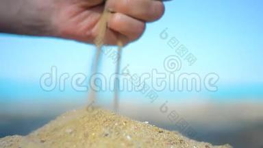 手特写放沙.. 沙子在<strong>蓝色</strong>的海洋上流过。 暑假海滩度假。