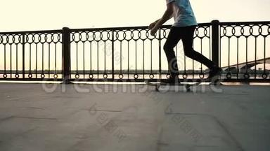 滑板上的人在日落时分在滑板上表演一个奥利触发器的跳跃，慢动作