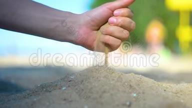 手特写放沙.. 沙子在<strong>蓝色</strong>的海洋上流过。 暑假海滩度假。