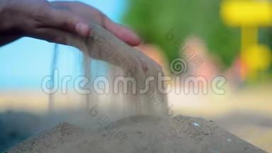 手特写放沙.. 沙子在蓝色的海洋上流过。 暑假海滩度假。
