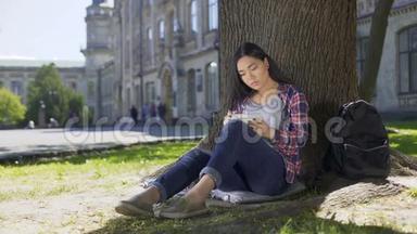 跨国青年妇女<strong>坐在树下</strong>写笔记，写文章